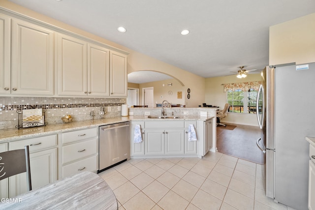 854 River Cliff Dr, Kodak, TN 37764 - kitchen featuring appliances with stainless steel finishes, arched walkways, a sink, a ceiling fan, and tasteful backsplash