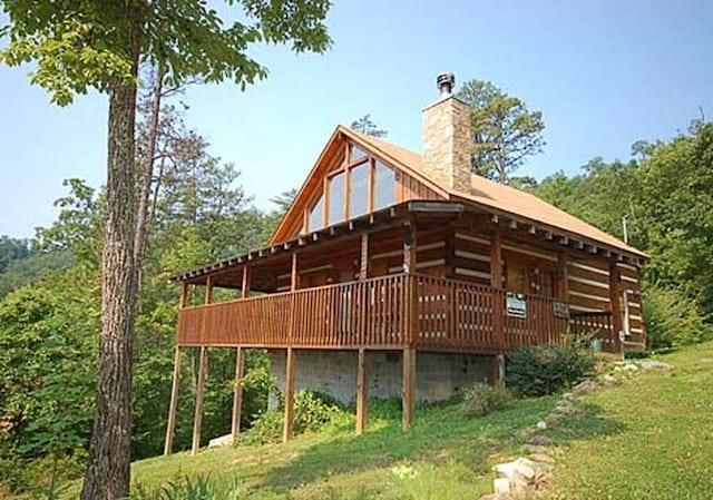 rear view of house featuring a lawn and a wooden deck