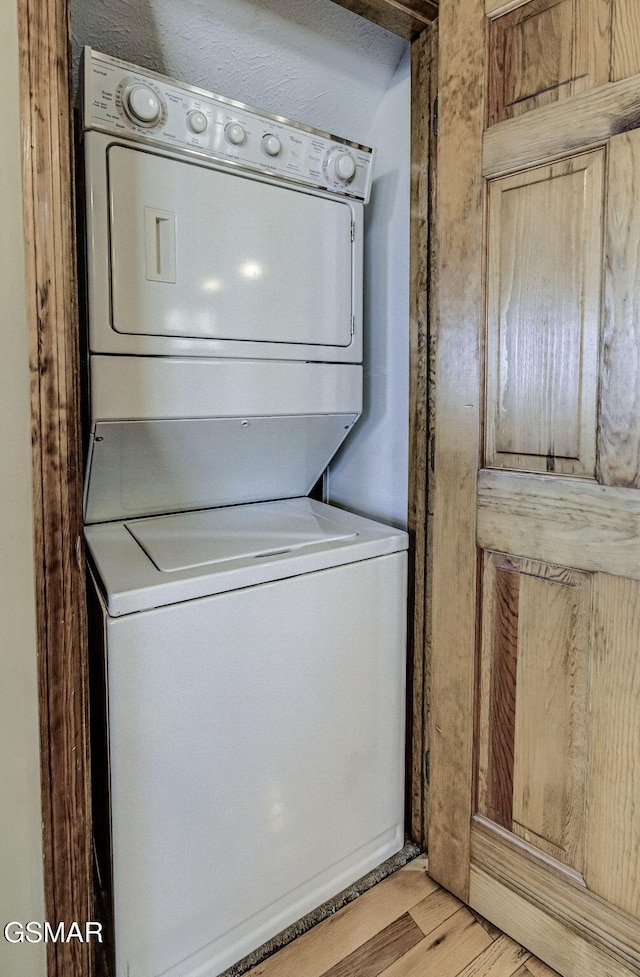 laundry room featuring light wood-type flooring, laundry area, and stacked washer and clothes dryer