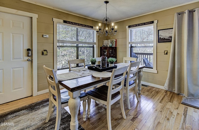 dining area with baseboards, visible vents, light wood finished floors, and an inviting chandelier