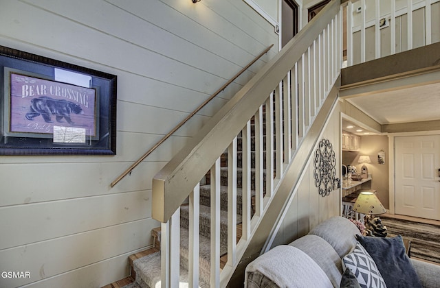 stairs with wooden walls and wood finished floors