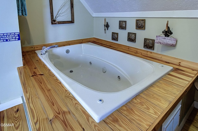 bathroom with a jetted tub and a textured ceiling