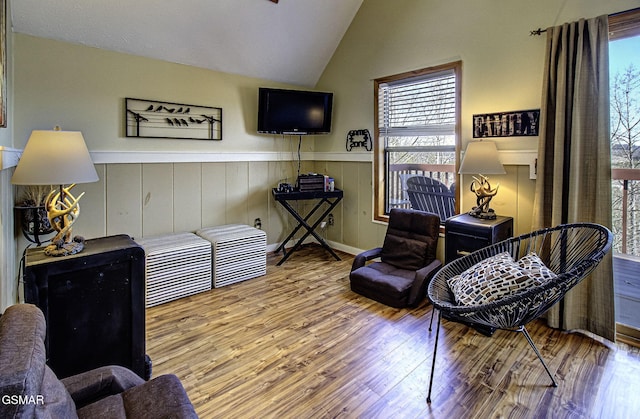 living area with lofted ceiling, a wainscoted wall, and wood finished floors