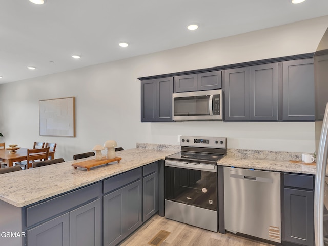 3141 Teaster Ln Unit 2, Pigeon Forge, TN 37863 - kitchen featuring appliances with stainless steel finishes, a peninsula, light wood-style floors, light stone counters, and recessed lighting