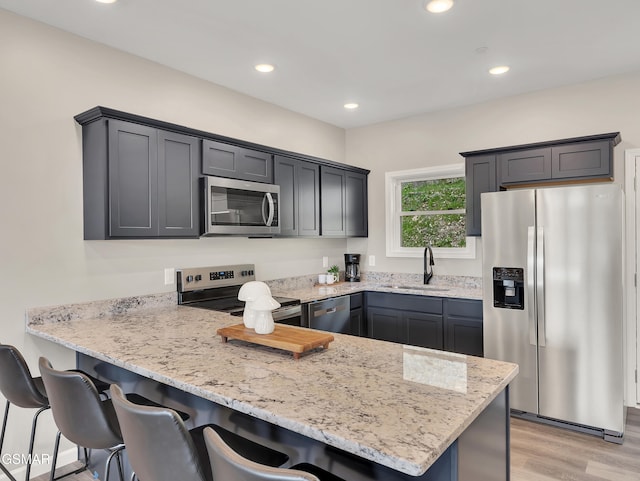 3141 Teaster Ln Unit 2, Pigeon Forge, TN 37863 - kitchen featuring stainless steel appliances, a peninsula, a breakfast bar, light stone counters, and light wood-style flooring