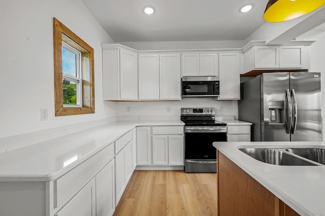 kitchen with sink, white cabinetry, stainless steel appliances, and light hardwood / wood-style flooring