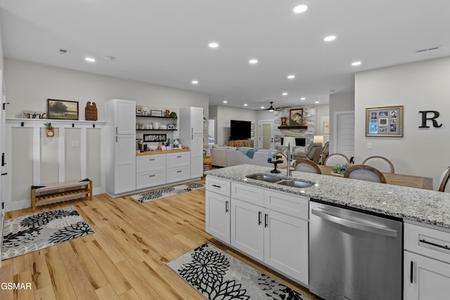 1032 Patriots Dr, Dandridge, TN 37725 - kitchen with dishwasher, a large fireplace, light wood finished floors, light stone counters, and white cabinets