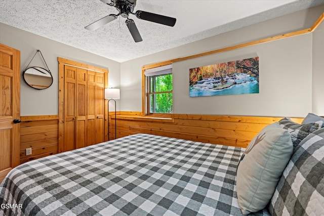 308 Brown Wren Way, Gatlinburg, TN 37738 - bedroom featuring a wainscoted wall, wood walls, a textured ceiling, and a ceiling fan