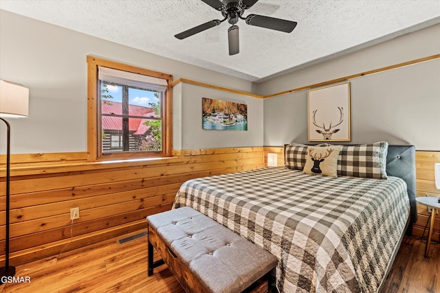 308 Brown Wren Way, Gatlinburg, TN 37738 - bedroom with wood walls, wainscoting, wood finished floors, a textured ceiling, and a ceiling fan