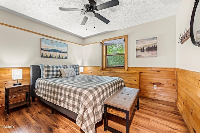 308 Brown Wren Way, Gatlinburg, TN 37738 - bedroom featuring wood walls, wood finished floors, a textured ceiling, wainscoting, and a ceiling fan