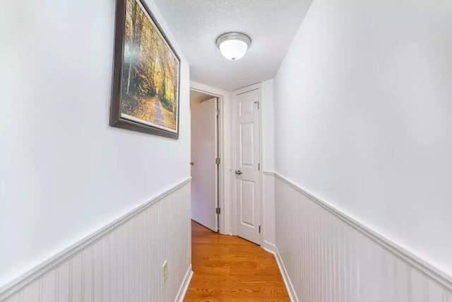 hallway with a textured ceiling and light wood-type flooring