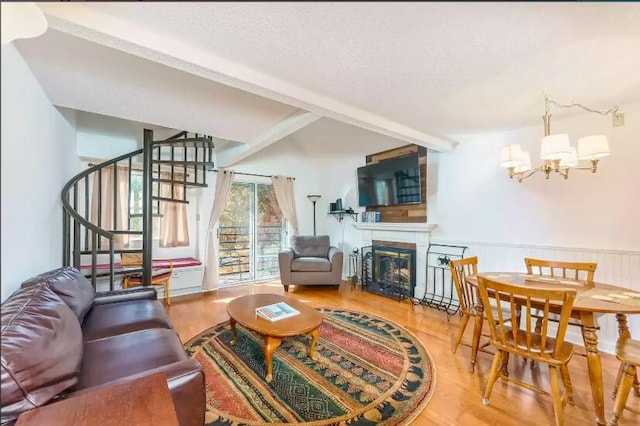 living room featuring beam ceiling, a textured ceiling, hardwood / wood-style flooring, and an inviting chandelier