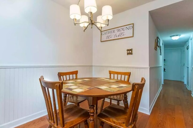 dining area with hardwood / wood-style flooring and an inviting chandelier