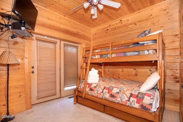 carpeted bedroom featuring wooden ceiling, ceiling fan, and wood walls