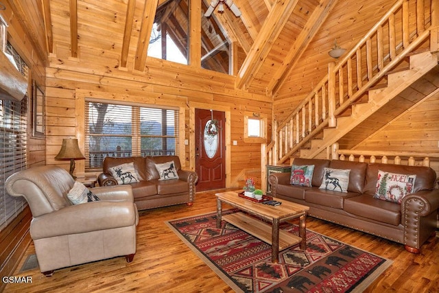 living room with high vaulted ceiling, wooden walls, wooden ceiling, and beam ceiling