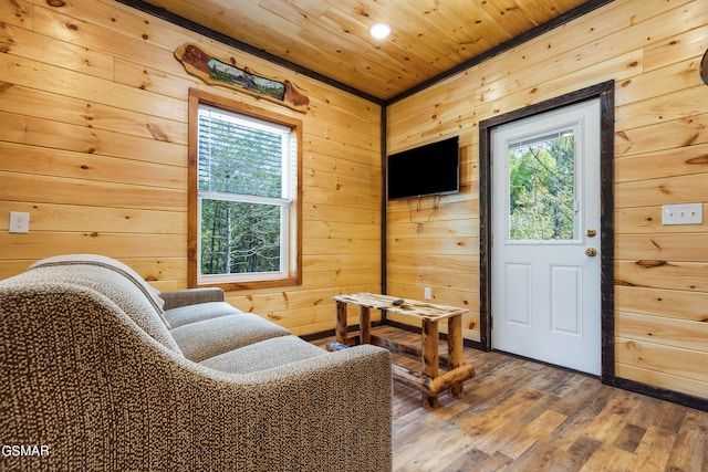 living area featuring a wealth of natural light, wood-type flooring, wooden ceiling, and wooden walls