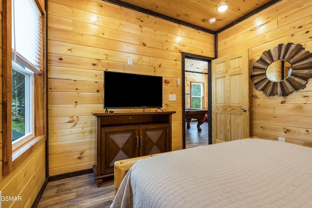 bedroom with multiple windows, wood walls, and dark hardwood / wood-style flooring