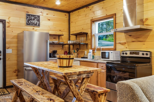 kitchen featuring island exhaust hood, stainless steel appliances, and wooden walls