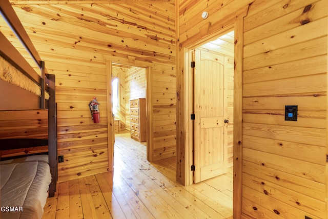 corridor with light hardwood / wood-style floors and wooden walls