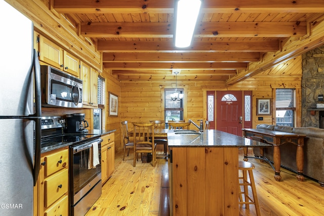 kitchen featuring a center island, a kitchen breakfast bar, beamed ceiling, decorative light fixtures, and stainless steel appliances