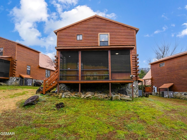 rear view of property with central air condition unit, a sunroom, and a yard