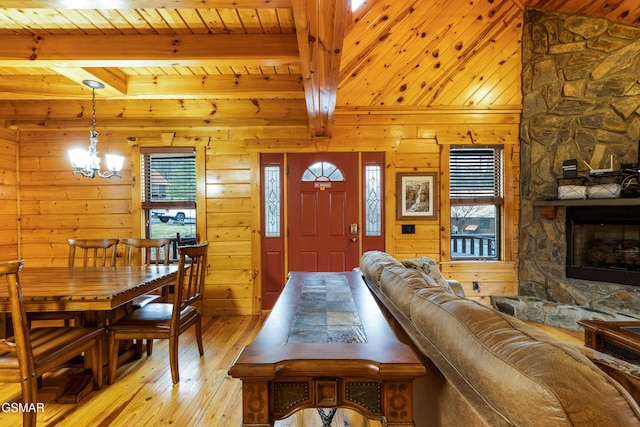 living room featuring wood walls, wooden ceiling, a stone fireplace, beam ceiling, and light hardwood / wood-style floors