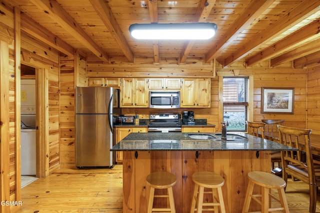 kitchen featuring a breakfast bar area, wood walls, sink, and appliances with stainless steel finishes