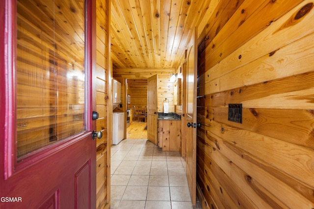 hall with light tile patterned floors, wood ceiling, and wood walls