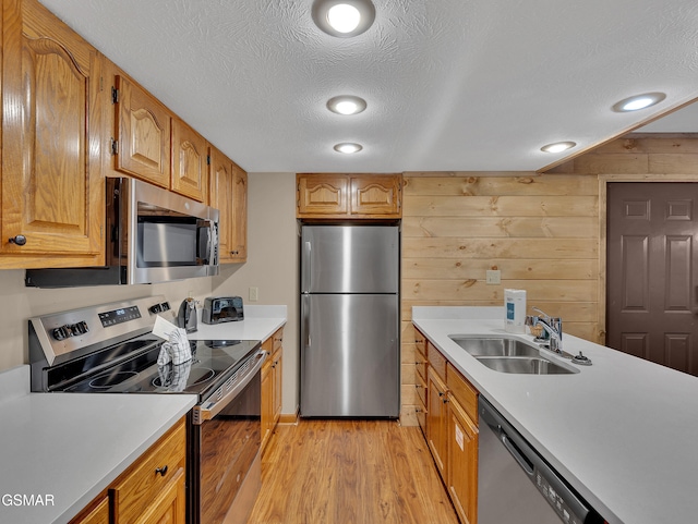 2733 Timber Way, Pigeon Forge, TN 37863 - kitchen featuring appliances with stainless steel finishes, a sink, light wood finished floors, light countertops, and wooden walls