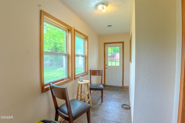 entryway featuring a textured wall, baseboards, and tile patterned floors
