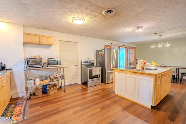 kitchen featuring visible vents, light brown cabinets, light wood-type flooring, a textured ceiling, and appliances with stainless steel finishes