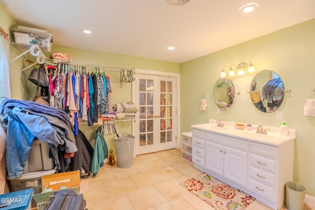bathroom with recessed lighting, double vanity, french doors, and a sink
