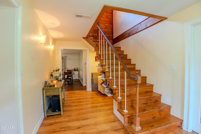 stairs with baseboards, wood finished floors, and visible vents