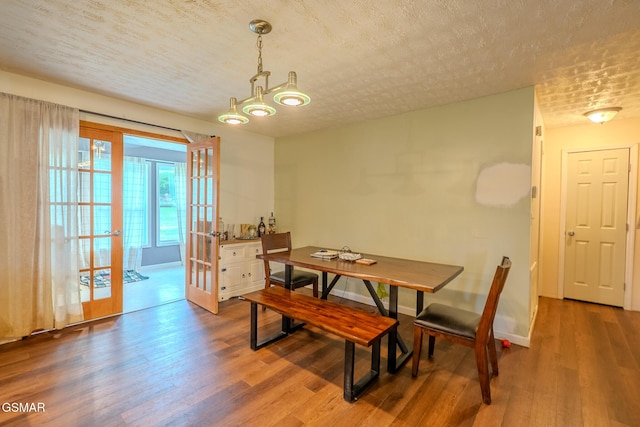 dining space with baseboards, french doors, wood finished floors, and a textured ceiling