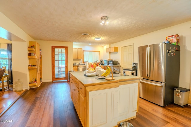 kitchen with a center island, a textured ceiling, light countertops, appliances with stainless steel finishes, and dark wood-type flooring