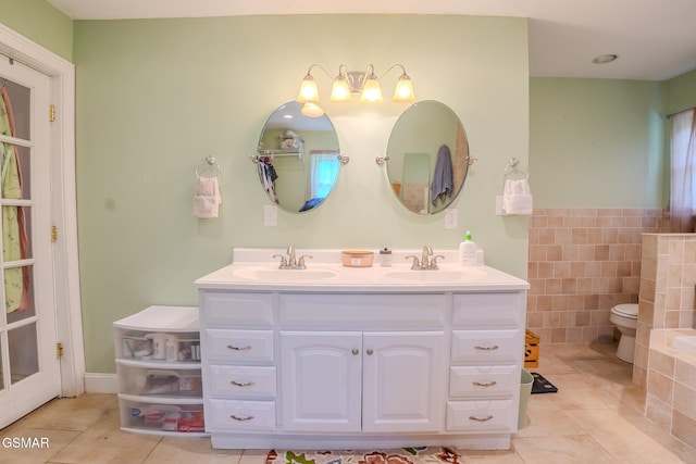 bathroom featuring tiled tub, tile patterned floors, a sink, and double vanity