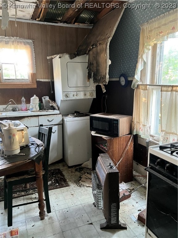 kitchen featuring white stove, sink, light tile patterned flooring, and stacked washer / drying machine