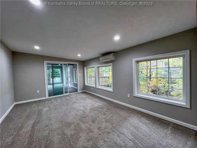 unfurnished room with a wealth of natural light, a wall mounted air conditioner, and dark colored carpet