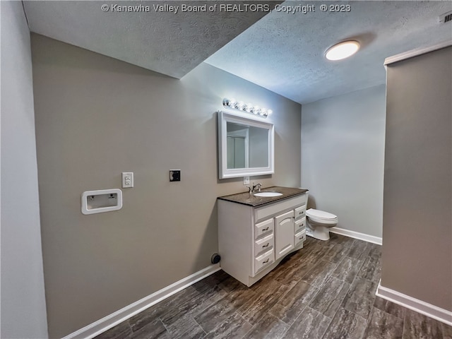 bathroom with vanity, a textured ceiling, wood-type flooring, and toilet