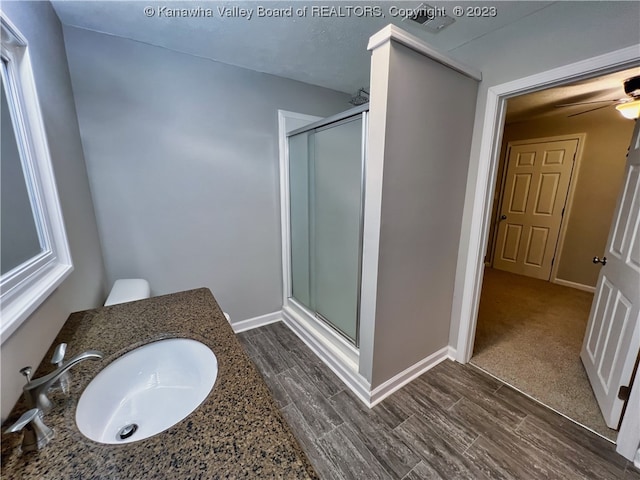 bathroom featuring wood-type flooring, a shower with door, ceiling fan, and vanity