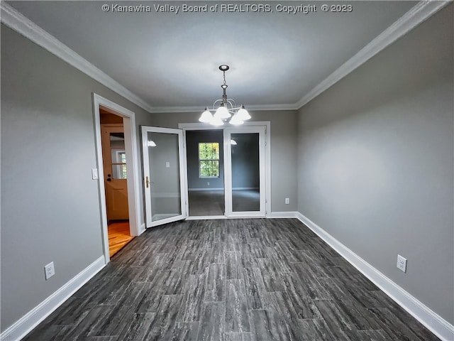 spare room featuring dark wood-type flooring, ornamental molding, and a chandelier