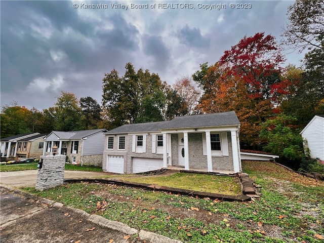 bi-level home with covered porch, a front yard, and a garage