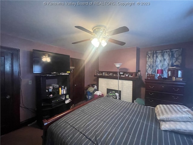 bedroom featuring ceiling fan and a brick fireplace