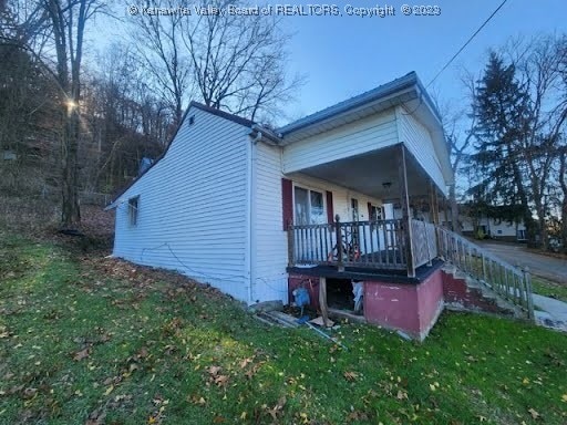 back of property with a lawn and covered porch