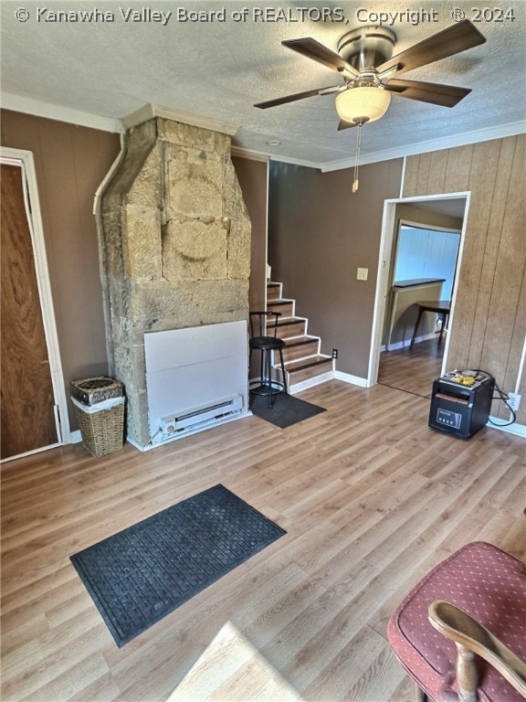 living room featuring ornamental molding, light hardwood / wood-style floors, ceiling fan, and a textured ceiling