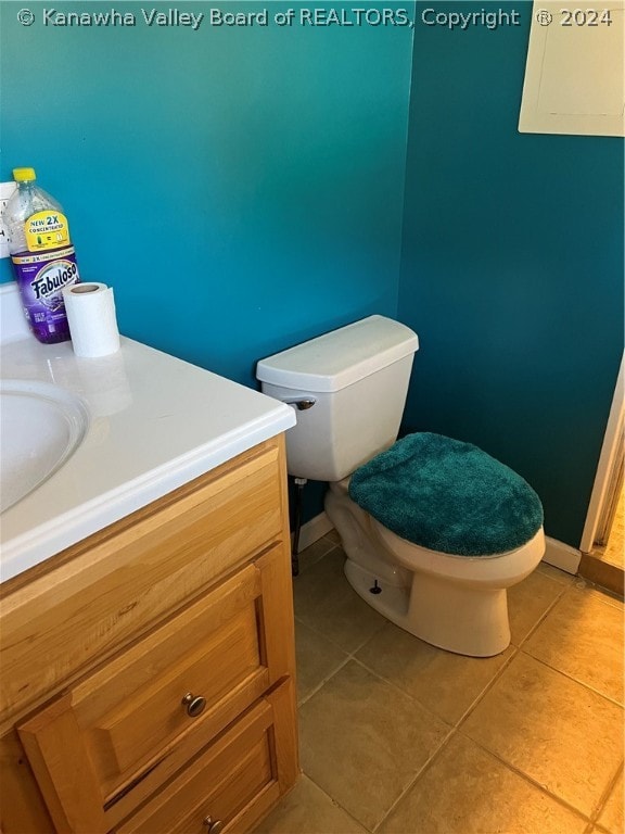 bathroom with toilet, vanity, and tile flooring