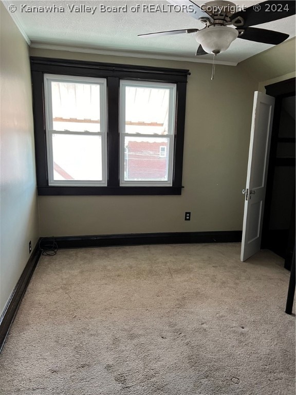 carpeted empty room with plenty of natural light, ornamental molding, and ceiling fan