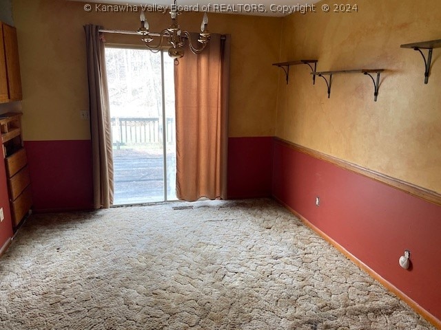 carpeted empty room featuring a chandelier