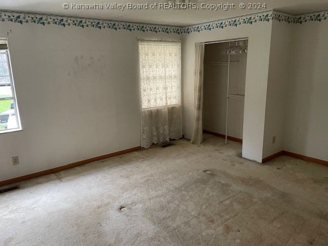 unfurnished bedroom with a closet and light colored carpet