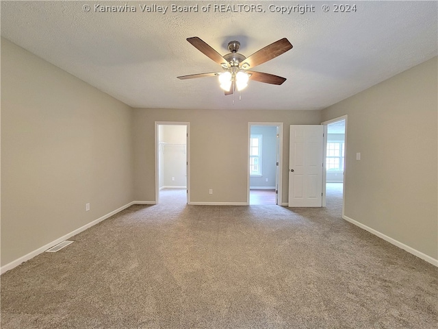 empty room featuring ceiling fan, light colored carpet, and a textured ceiling